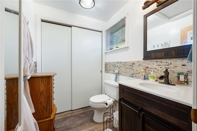 bathroom featuring toilet, backsplash, wood finished floors, and vanity