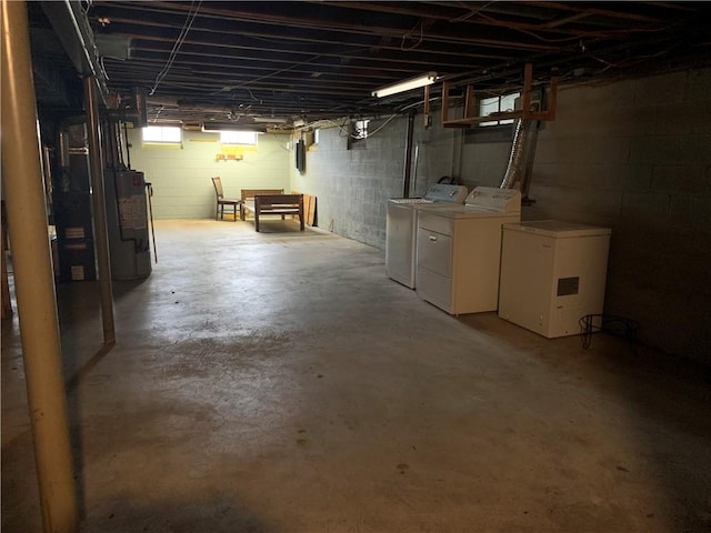 below grade area featuring water heater, separate washer and dryer, and refrigerator