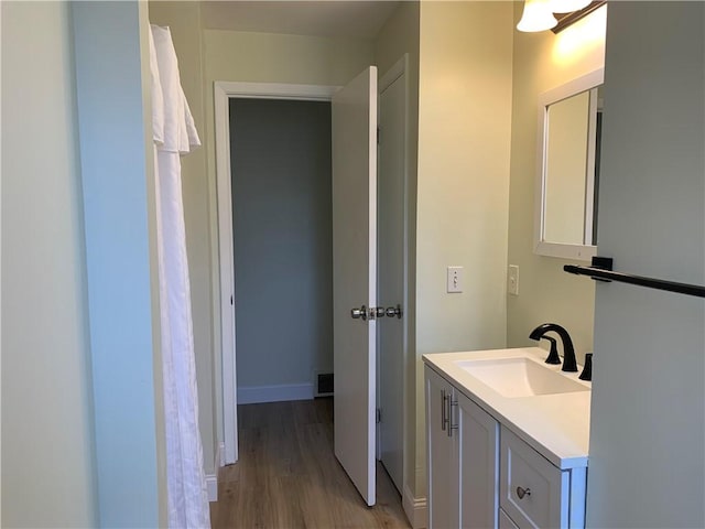 bathroom featuring wood finished floors, vanity, visible vents, and baseboards