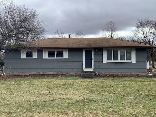 ranch-style home with entry steps, roof with shingles, and a front yard