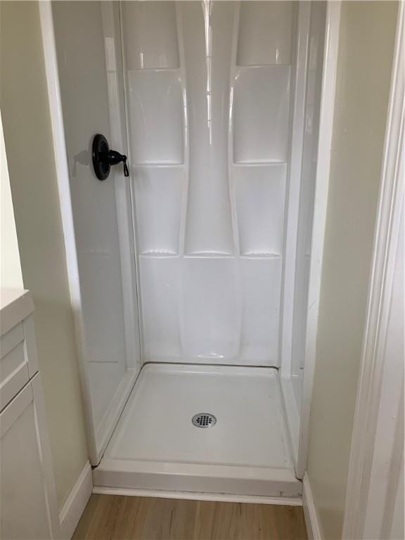 full bath featuring a shower stall, wood finished floors, and vanity