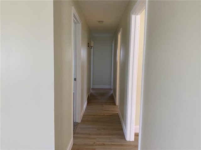 corridor featuring light wood-type flooring and baseboards