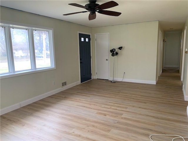 spare room featuring light wood finished floors, visible vents, and baseboards