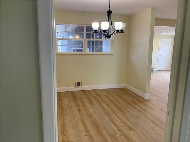 unfurnished dining area featuring a chandelier, light wood-style flooring, visible vents, and baseboards