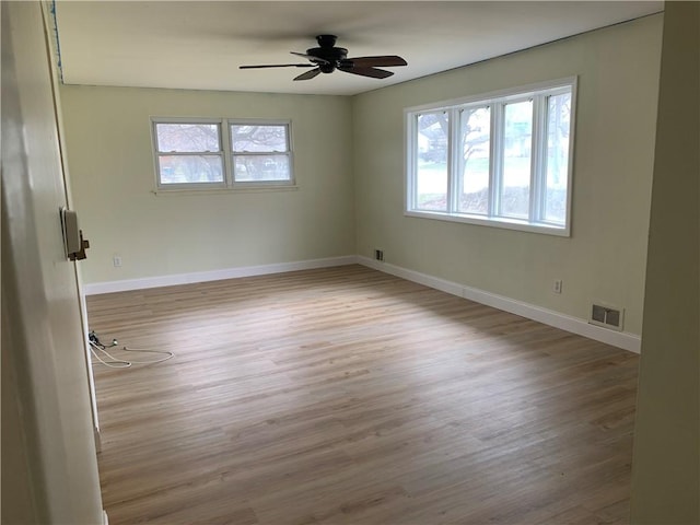 spare room with plenty of natural light, wood finished floors, visible vents, and baseboards