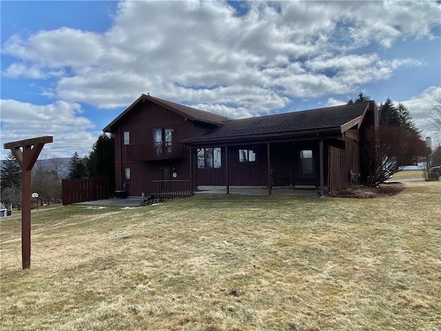 rear view of property featuring a balcony and a lawn