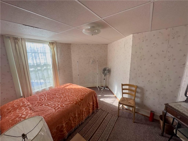 carpeted bedroom featuring baseboards, a drop ceiling, and wallpapered walls