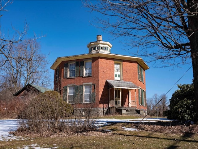 view of front of home featuring brick siding and a chimney