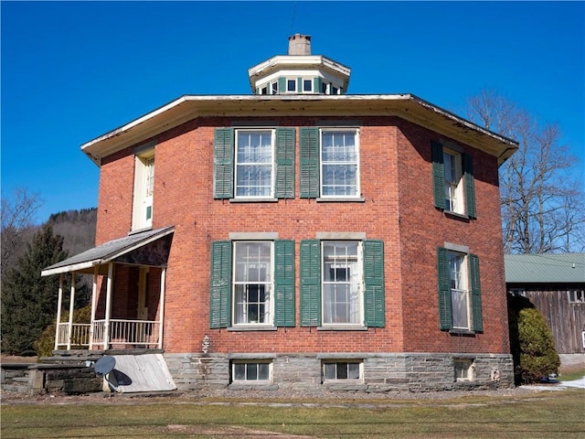 view of side of home with a chimney and brick siding