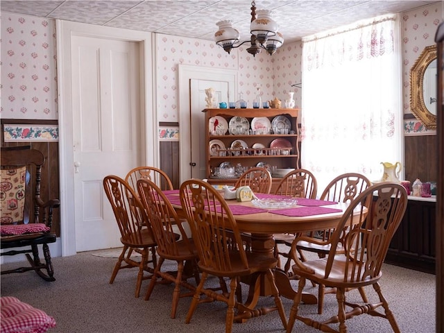 dining space with carpet, an inviting chandelier, and wallpapered walls