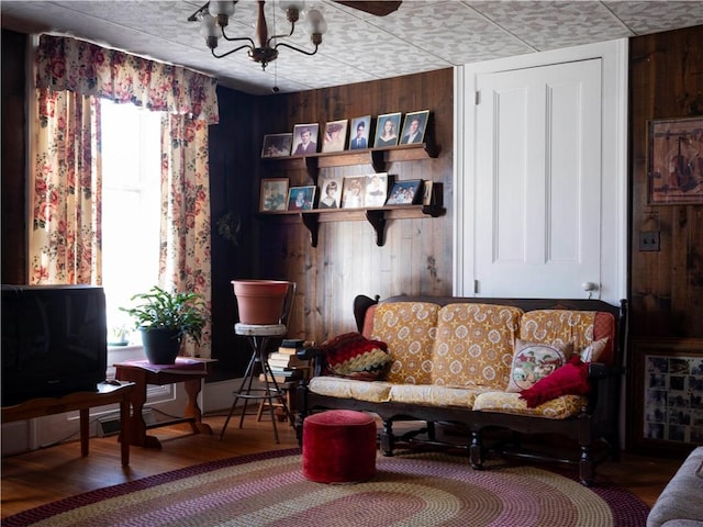 sitting room featuring a chandelier, wood finished floors, and wooden walls