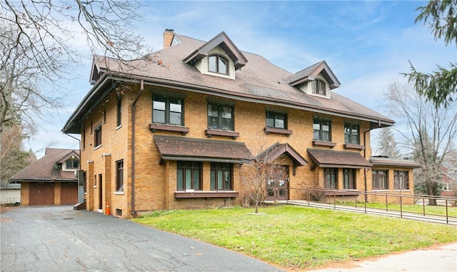 view of front of house with brick siding, a chimney, a front lawn, and fence