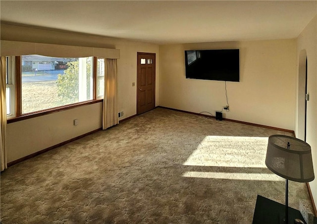 unfurnished living room featuring carpet, visible vents, and baseboards