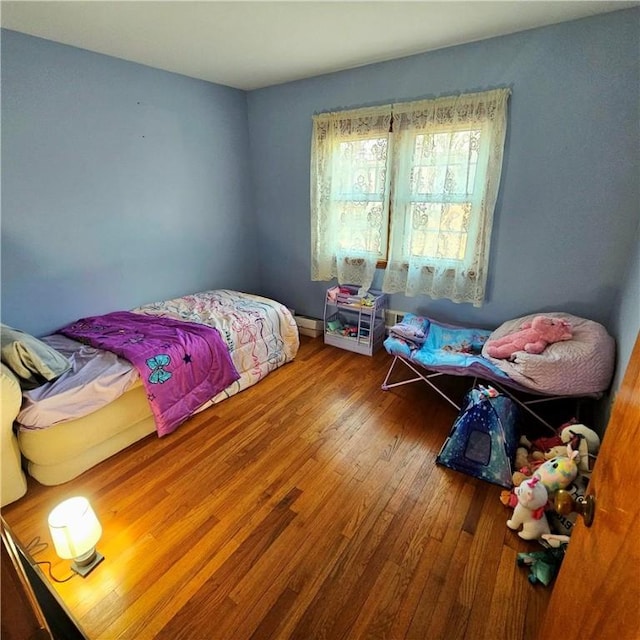 bedroom with a baseboard heating unit and hardwood / wood-style flooring