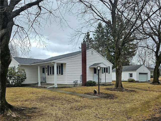 ranch-style house featuring a chimney, an outdoor structure, a detached garage, and a front yard