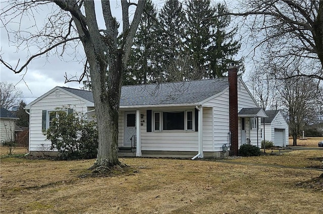 ranch-style home with entry steps, a shingled roof, a chimney, and a front yard