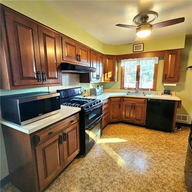 kitchen with black appliances, under cabinet range hood, light countertops, and a sink