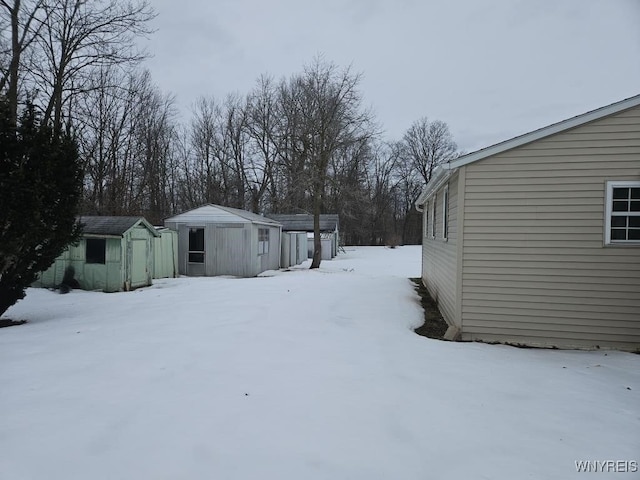 yard covered in snow with a shed and an outdoor structure