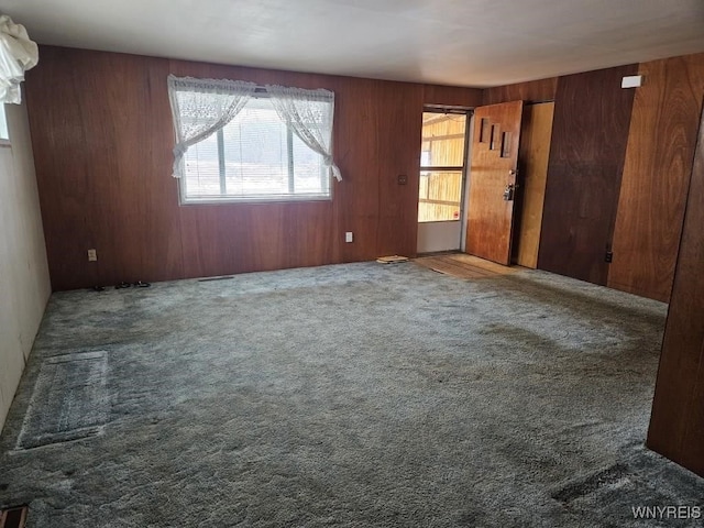 carpeted spare room featuring wooden walls