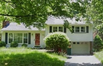 split level home featuring driveway, a chimney, and an attached garage