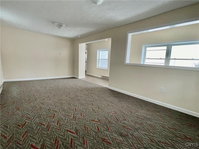 carpeted empty room with a baseboard radiator, a textured ceiling, and baseboards