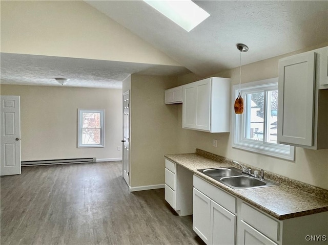 kitchen featuring a textured ceiling, a baseboard heating unit, a sink, and wood finished floors