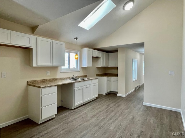 kitchen featuring lofted ceiling, white cabinetry, a sink, and wood finished floors