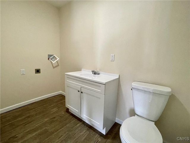 half bathroom with toilet, baseboards, wood finished floors, and vanity