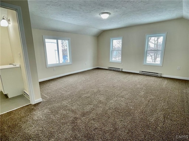 spare room featuring vaulted ceiling, dark colored carpet, and baseboard heating