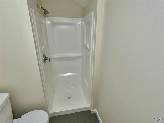 full bathroom featuring toilet, a shower stall, and baseboards