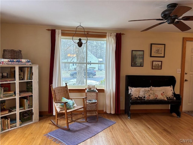 living area featuring ceiling fan, baseboards, and wood finished floors