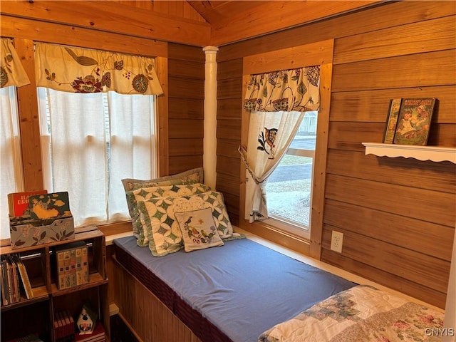 bedroom featuring lofted ceiling, decorative columns, and wooden walls