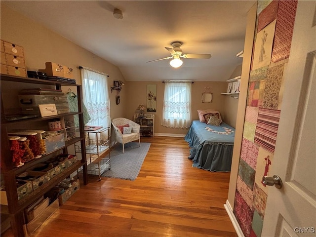 bedroom featuring multiple windows, baseboards, vaulted ceiling, and wood finished floors