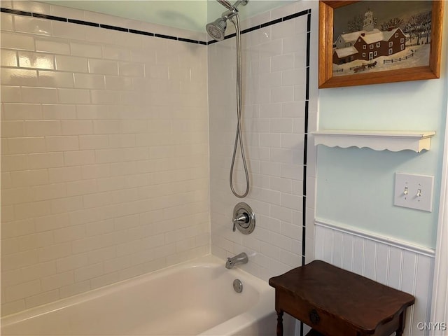 bathroom featuring a wainscoted wall and shower / washtub combination