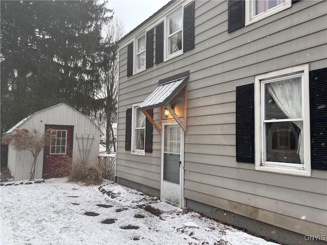 snow covered property featuring a shed and an outdoor structure