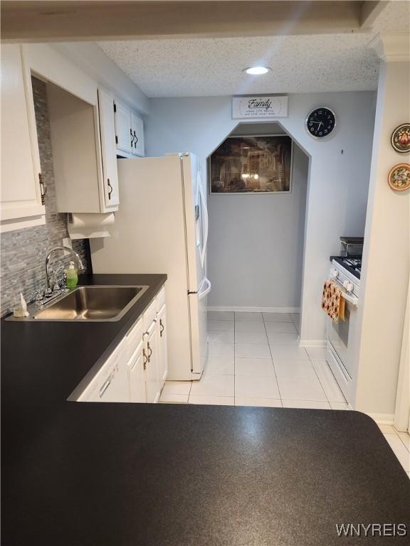 kitchen featuring white appliances, a sink, white cabinets, and decorative backsplash