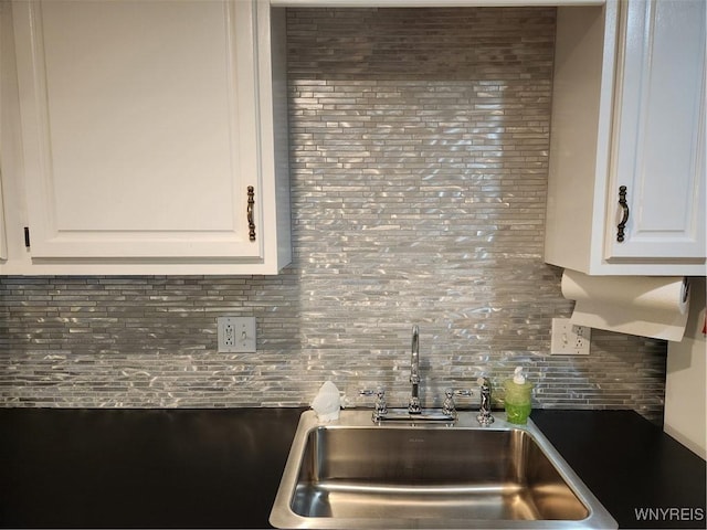 kitchen featuring tasteful backsplash, white cabinetry, and a sink