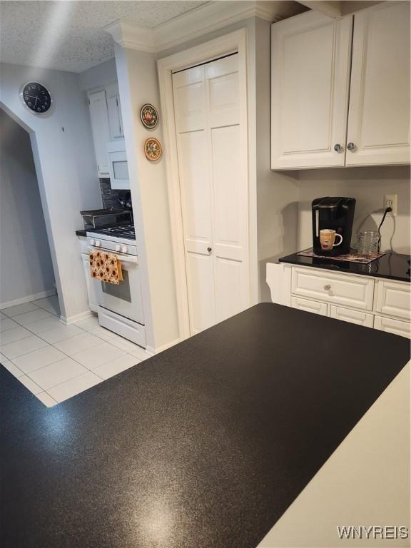 kitchen featuring a textured ceiling, white appliances, white cabinets, tasteful backsplash, and dark countertops