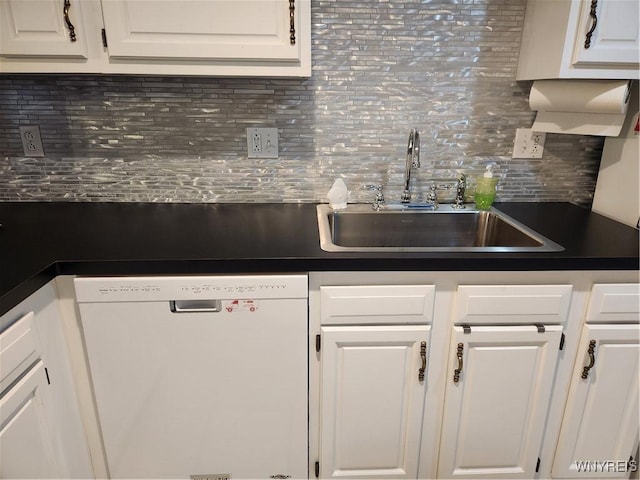 kitchen with dark countertops, white cabinets, white dishwasher, and a sink