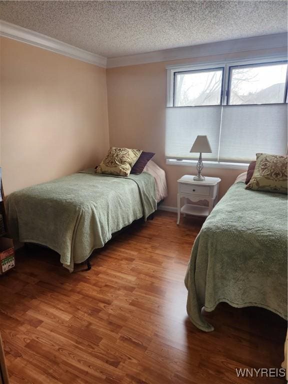 bedroom with crown molding, a textured ceiling, and wood finished floors