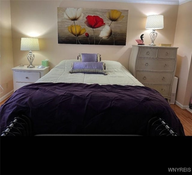 bedroom with ornamental molding, wood finished floors, and baseboards