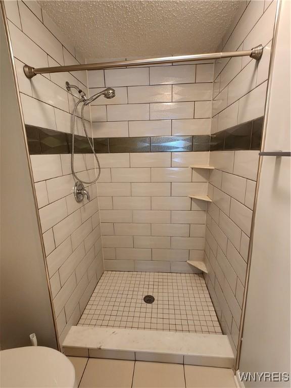 bathroom featuring a stall shower, a textured ceiling, and toilet