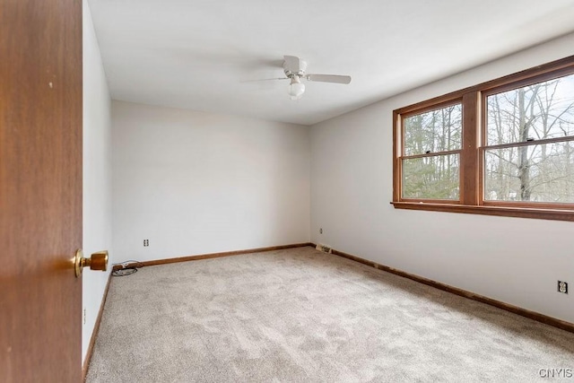 spare room with carpet floors, a ceiling fan, and baseboards