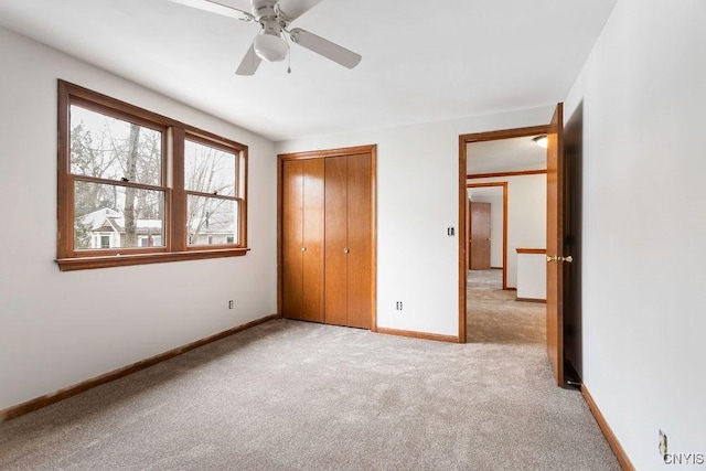 unfurnished bedroom featuring baseboards, ceiling fan, a closet, and light colored carpet