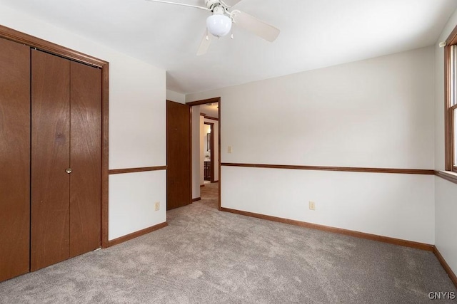 unfurnished bedroom with baseboards, ceiling fan, a closet, and light colored carpet