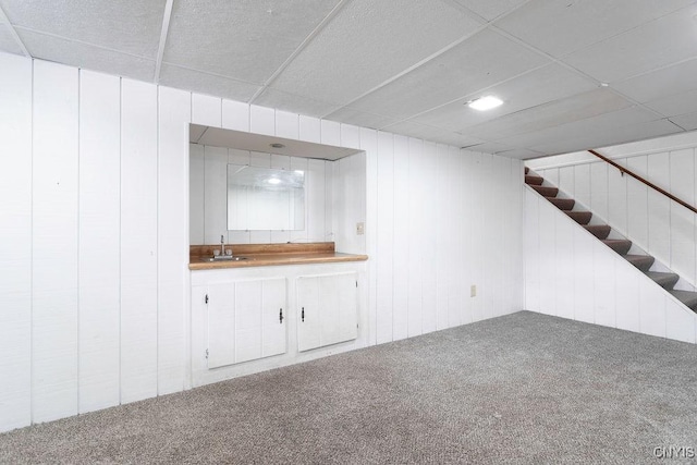 interior space featuring stairs, a drop ceiling, a sink, and carpet flooring