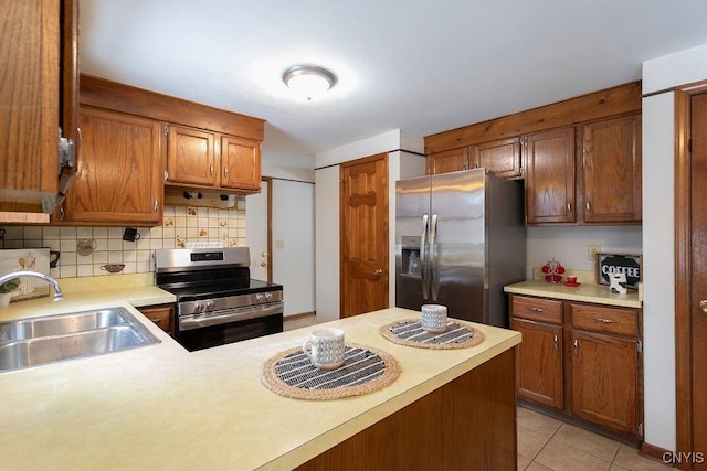 kitchen featuring light tile patterned floors, stainless steel appliances, a sink, light countertops, and decorative backsplash