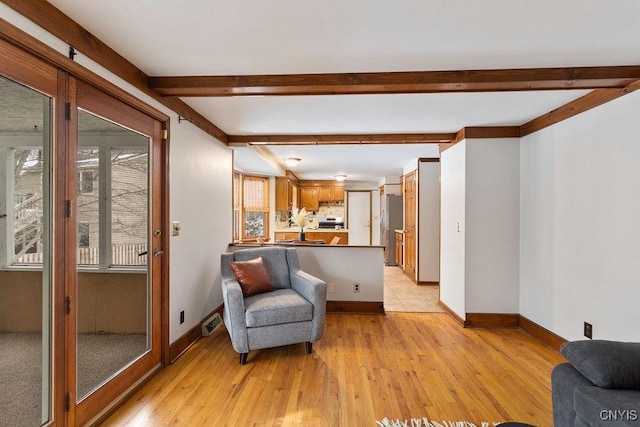 sitting room with light wood-style flooring, visible vents, baseboards, and beamed ceiling