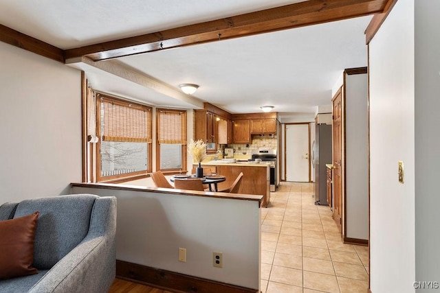 kitchen with open floor plan, beamed ceiling, a peninsula, stainless steel appliances, and backsplash