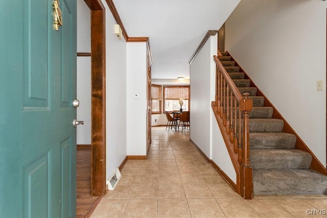 foyer featuring light tile patterned floors, stairs, visible vents, and baseboards